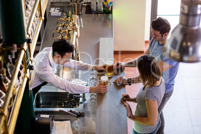 Bartender serving beer to couple