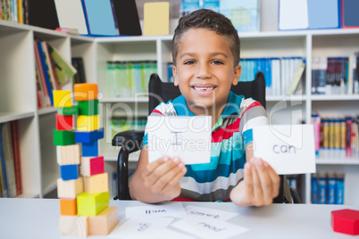 Disabled boy showing placard that reads I Can in library