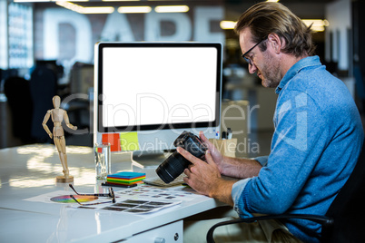 Creative businessman holding camera at computer desk