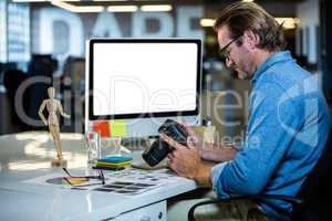 Creative businessman holding camera at computer desk