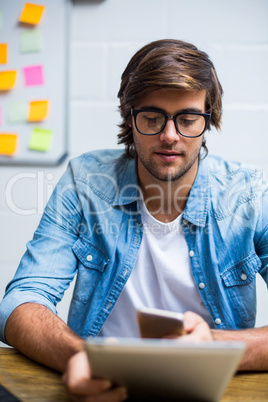 Man using digital tablet and mobile phone in office