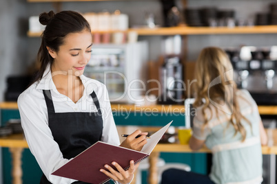 Smiling waitress writing in a file