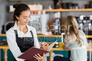 Smiling waitress writing in a file