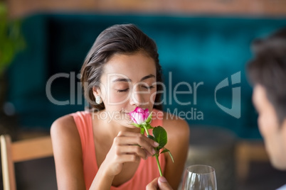 Woman smelling a rose offered by man