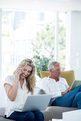 Smiling woman talking on phone by man using tablet