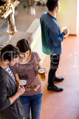 Woman showing cellphone to boyfriend while having beer