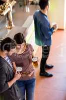 Woman showing cellphone to boyfriend while having beer