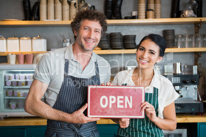 Portrait of waiter and waitress holding open signboard