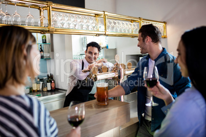 Friends talking to bartender while having drinks