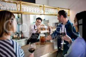 Friends talking to bartender while having drinks