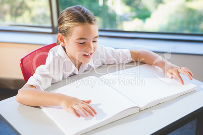 Schoolkid reading braille book in classroom