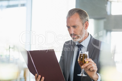 Businessman holding glass of beer and looking at menu