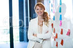 Smiling businesswoman leaning on whiteboard