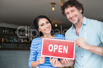 Couple holding open signboard