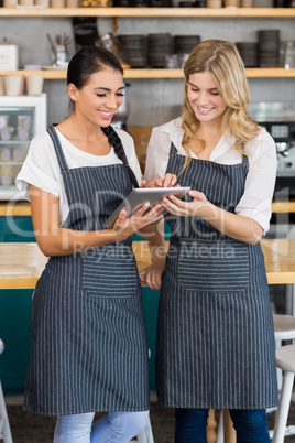 Smiling two waitresses using digital tablet