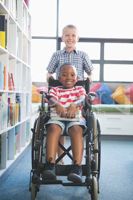 Happy schoolboy carrying his friend in wheelchair