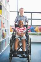 Happy schoolboy carrying his friend in wheelchair