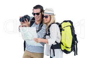 Couple looking in camera while carrying luggage
