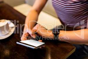 Woman using smartphone at table in restaurant