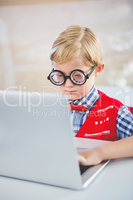 Close-up of schoolkid using laptop in classroom