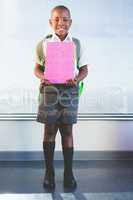 Happy schoolkid holding books and standing in classroom