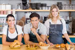 Smiling waiter and two waitresses leaning on counter