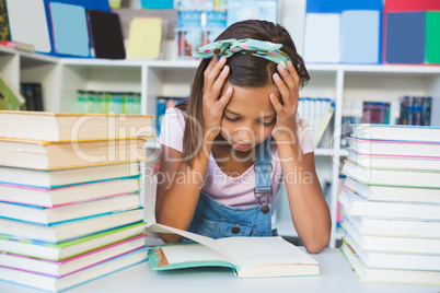 School girl reading a book in library