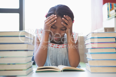 School girl reading a book in library