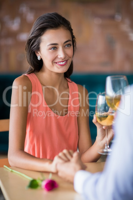 Couple holding hands while having glass of wine