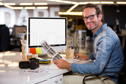 Smiling photo editor sitting at computer desk