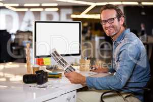 Smiling photo editor sitting at computer desk