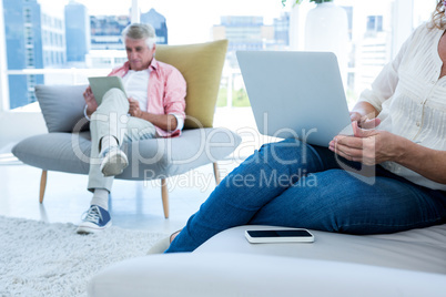 Midsection of woman using notebook with man at home