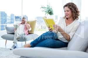 Smiling mature woman reading book at home
