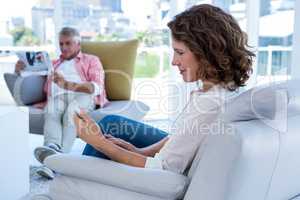 Woman using phone while man reading newspaper