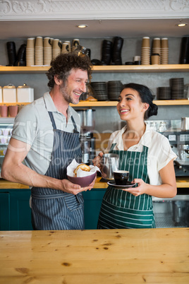 Waiter and waitress holding bowl with snack and coffee cup