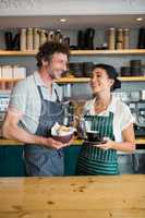Waiter and waitress holding bowl with snack and coffee cup