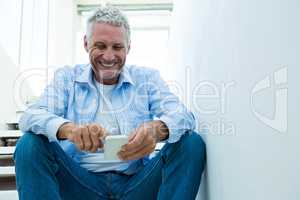 Happy mature man using smartphone at home