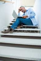 Tensed man using laptop on steps