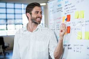 Businessman smiling while pointing on sticky note