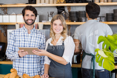 Smiling man and waitresses standing at counter using digital tab