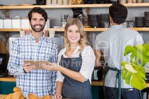 Smiling man and waitresses standing at counter using digital tab