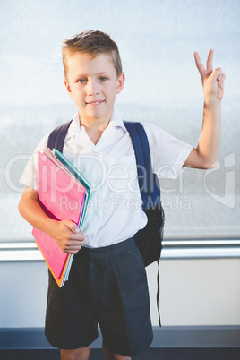 Happy schoolkid holding books and standing in classroom