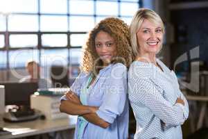 Confident female colleagues standing back to back