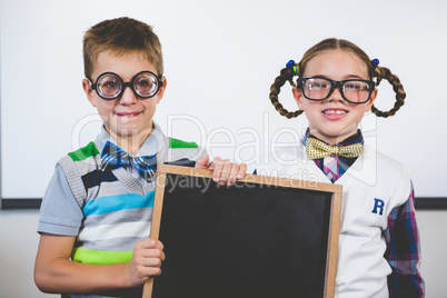 Portrait of smiling school kids holding slate in classroom