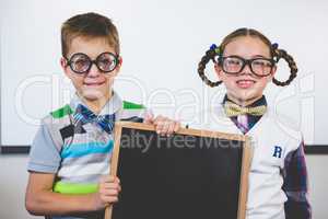 Portrait of smiling school kids holding slate in classroom