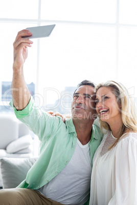 Smiling couple taking selfie at home