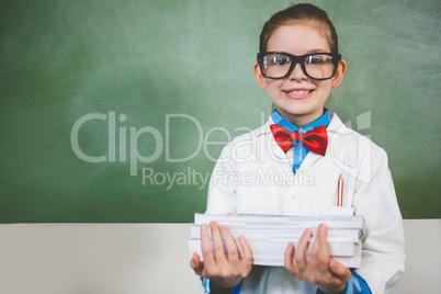 Portrait of smiling girl standing with a stack of books in class