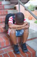 Sad schoolboy sitting alone on staircase