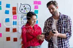 Young colleagues using mobile phones in creative office