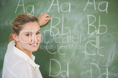 Smiling teacher teaching on chalkboard in classroom